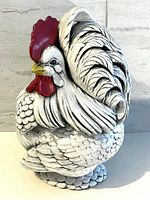 White rooster ceramic cookie jar showing detailed feather texture and painted red comb and wattles, yellow beak, black feather accents.