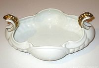Front angled view showing ornate gilt handles and scalloped edges of white porcelain tureen.