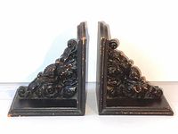 Pair of vintage ebony wood Victorian floral carved bookends shown side by side with detailed floral scrollwork and distressed finish on a white background.