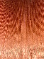 Close-up showing vertical linear weave pattern and natural fiber texture in earthy orange color.