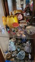 Shelf with yellow tulip ceramic vase, small ceramic animal figurines, Adams china creamer and cup with scenic prints, and other assorted figurines