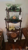 Full view of the five-tier wooden display shelf with various glassware and decorative items arranged on each tier.