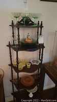 Photo showing the wooden tiered stand with all glassware, bowls, plates, figurine, and pitcher arranged on shelves.