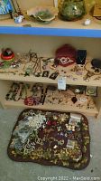 Wide view of shelves and surface with assorted vintage jewelry including necklaces, brooches, rings, earrings on display and laid out on fabric