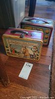 Photo showing two metal lunchboxes placed on floor; front one Roy Rogers and Dale Evans themed, back one Bugs Bunny themed
