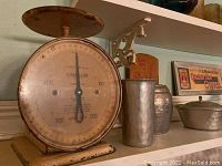 Photo of vintage Chatillon metal kitchen scale, silver metal container, and lidded metal bowl on shelf with vintage coffee sign