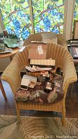 Wicker armchair with stacked boxes and miscellaneous small boxed items on seat.