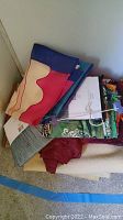 Folded assorted linens and fabric pieces piled, showing various colors and patterns