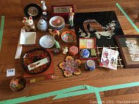 Full layout of all Asian-inspired home decor items on wooden floor, showing lacquered plates, figurines, bowls, and wall decor pieces.