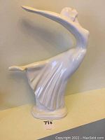 Front view of white ceramic figurine showing dancing woman arching back with extended arms and flowing skirt.