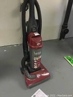 Full view of Dirt Devil Scorpion bagless upright vacuum on floor with hose attachment wrapped around.