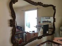 Front view showing the rectangular mirror with ornate carved wooden frame and reflective glass surface.