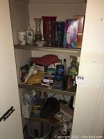 Wide view of closet shelves containing glass vases, ceramic jars, tissue box, personal care items, household tools, cleaning supplies and vacuum cleaner.