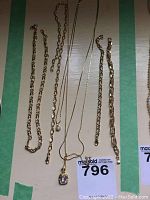 Full set of gold-tone costume jewelry including necklaces and bracelets shown on a cardboard background