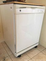 Full view of Kenmore portable dishwasher showing white body, control panel location, and wood-tone top surface.