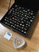 Full view of black felt-lined tray holding rows of costume rings and heart-shaped glass tray