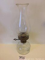 Full view of the glass oil lamp showing clear glass base with hobnailed rim and chimney with metal burner.