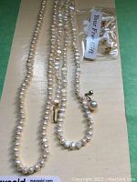 Full view of two freshwater pearl necklaces, a pearl pendant, and a pair of earrings in small plastic bag labeled 'Your Free Gift'.
