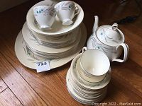 Stacked view of cups, plates, and teapot showing the Harvest Song pattern and overall set composition
