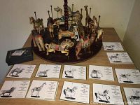 Full view of carousel display with all 12 animal mounts on two tiers and corresponding booklets fanned out in front, plus black presentation box.