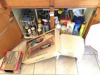 Photo of under sink storage showing assorted kitchen chemicals along with two beige plastic stools and the Winsome Wood beechwood bed tray box