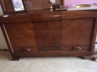 Front view of wooden chest showing lockable top and pullout bottom drawer with decorative wood grain.