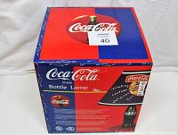 Top and front views of the original Coca-Cola bottle lamp box showing branding and design details.