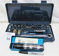 Photo showing the Royal ratchet socket set open with various sockets, ratchet wrench, extensions, and spark plug sockets arranged neatly inside the case along with a maxsold card.