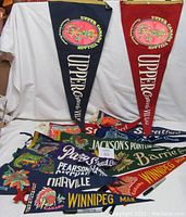 A group of ten smaller felt pennants displaying various Canadian locations with colorful graphics and text.