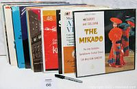 Photo of 8 sealed classical music LP records standing upright, showing album covers including The Mikado by Gilbert and Sullivan, and others with classical music themes.