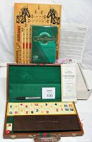 Overview of the three games including Rummy Cube set with numbered tiles arranged in wooden travel case, Slang Teasers card game in green sealed packaging, vertical scoring board for Poker Derby with horse illustrations and numbers, and game instructions.