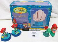 Photo showing original sealed retail box for Disney The Little Mermaid Telephone with handset base and four Ariel figurines in front. Also includes a pen for size reference.