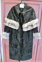 Black Persian Lamb fur coat with chinchilla fur trim on cuffs and elongated cape back. Front view shows collar and fastener.