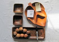 Overall view of the carved Kumani wood items: leaf-shaped serving tray, rectangular tray, 8 napkin rings, and 3 serving bowls