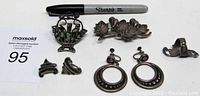 Sterling silver jewelry lot with all seven pieces displayed, including two brooches, two pairs of earrings, and one ring.