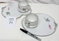Photo showing two snack plate and cup sets with hand painted rosebud design, white plates with silver trim, and matching white cup.