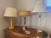 Three vintage lamps displayed on wooden surface with two extension cords coiled in front.