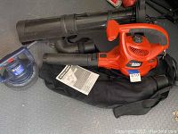 Photo of Black & Decker electric blower vac with removable nozzle, collection bag, and instruction manual alongside blue Wen electric auto detail polisher.