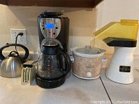 Overview of all items on kitchen counter: Mr. Coffee coffee maker, Rival mini crockpot, Presto popcorn popper, kitchen scale, and teapot