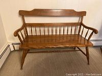 Front view of Ethan Allen wooden bench showing arched backrest, spindle back, and turned legs.