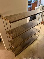 Photo showing four-shelf metal bookshelf with wood-patterned shelving and tubular metal frame