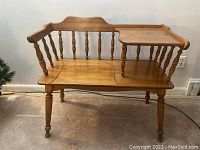 Front angle view of oak telephone table showing spindle backrest and side elevated platform on turned supports.