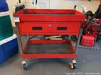 Front view of red metal rolling tool cart with drawer and open bottom shelf on caster wheels.