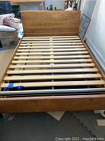 Full view of assembled metal and wood slatted full-size bed frame with solid live edge headboard.