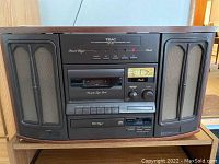 Front view of TEAC media console showing dual speakers, cassette deck, control buttons, and CD player.