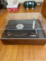 Full view of Sears Silvertone turntable record player with clear dust cover on woodgrain base.