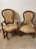 Two vintage mustard yellow and green floral pattern upholstered chairs with wood frames; one is an armchair with casters and rocker base, the other an armless side chair.