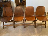 Front view of four wooden folding chairs side by side showing wood finish and condition.
