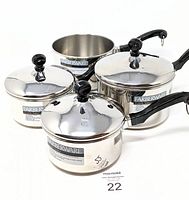 Set of four Farberware stainless steel pots with lids (three lids) and black handles, arranged side by side.