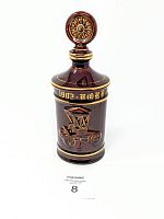 Front view of brown ceramic spirits decanter with embossed 1902 Ford Runabout car relief and gold detailing.